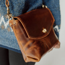 Load image into Gallery viewer, A close-up of a person wearing a blue knit sweater and carrying a brown leather crossbody bag with a flap closure and gold-tone hardware.