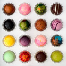 Load image into Gallery viewer, A white square box containing 16 decorated gourmet painted chocolates photographed from directly above.
